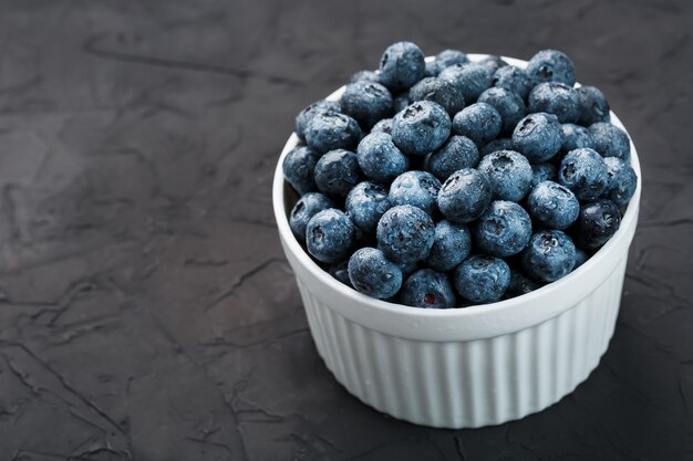 Blueberries in a white Cup on a black textured