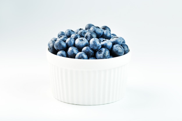 Blueberries in a white Cup on a white background. Isolate, free space