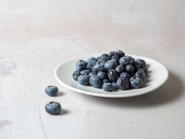 Blueberries on a white saucer on a concrete background