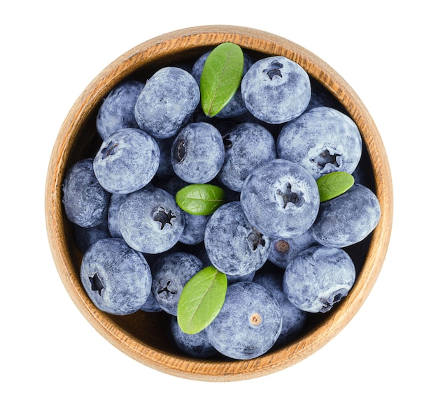 Blueberries with leaves in a round wooden plate on a white isolated background, top view