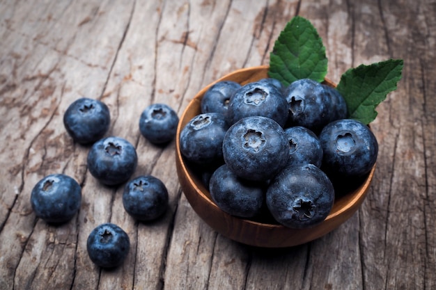 Blueberries in wood bowl on wooden table background.