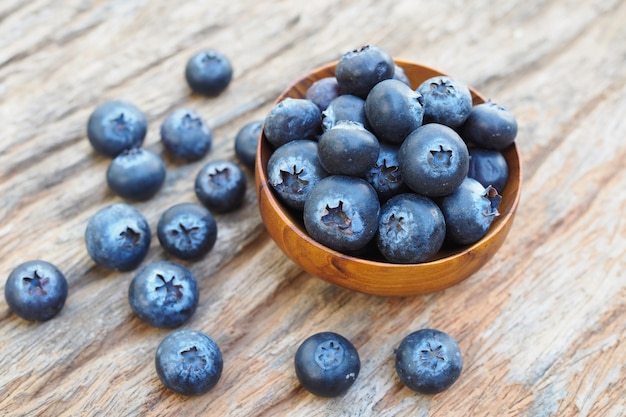 Blueberries in wooden bowls on old wooden table background