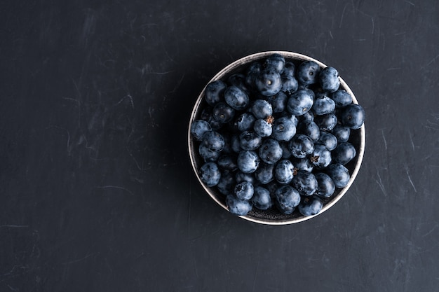 Blueberry antioxidant organic superfood in ceramic bowl concept for healthy eating and dieting nutrition Top view on dark black surface