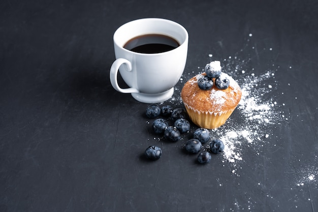 Blueberry antioxidant organic superfood and sweet muffin with cup of coffe  for healthy eating and dieting nutrition Top view on dark black 