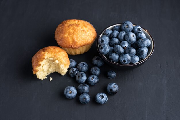 Blueberry antioxidant organische superfood in keramische kom en zoete muffin voor gezond eten en dieetvoeding Bovenaanzicht op donker zwart