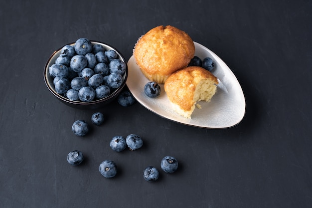 Blueberry antioxidant organische superfood in keramische kom en zoete muffin voor gezond eten en dieetvoeding Bovenaanzicht op donker zwart