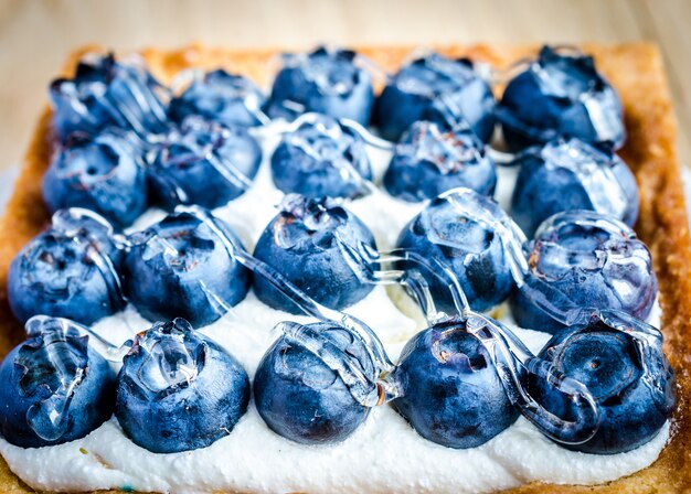 Blueberry cake with cream on a wooden table