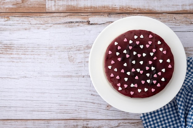 Blueberry cheesecake decorated with sweet hearts on wooden table