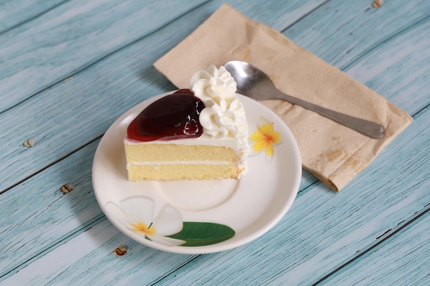 Домашний торт с черничным чизкейком на белой тарелке и ложке, сладкая десертная выпечка, фруктовый крем и чизкейк