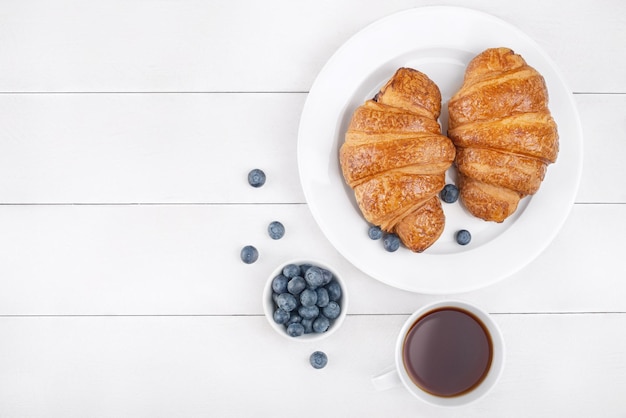 Photo blueberry croissants and black tea on white wooden background