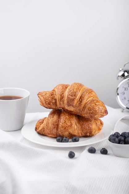 blueberry croissants and black tea on white wooden background