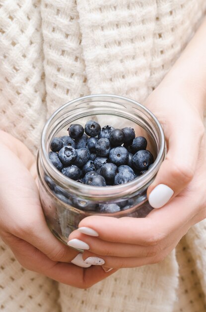 Blueberry in glass jar in female hands.