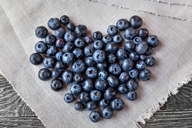 Blueberry heart lie on a homespun tablecloth on wooden background