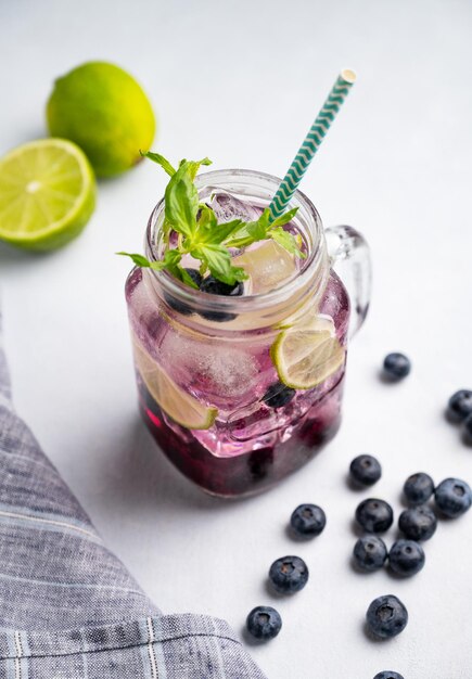 블루베리 모히토 (Blueberry mojito) 또는 레모네이드 (lemonade) 는 가운 배경에 베리 (berries) 와 과일 (fruit) 을 은 컵에 라임 얼음과 민트 (mint) 를 넣은 여름의 상쾌한 음료의 개념입니다.