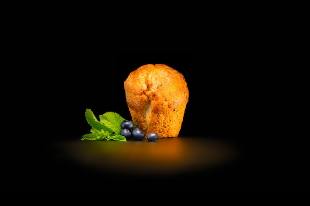 Blueberry muffin with blueberries and mint leaves. Isolated on black background.