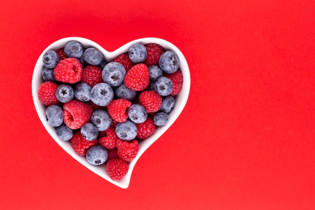 Blueberry and raspberries, fruit in a heart shaped dish on a porcelain bowl