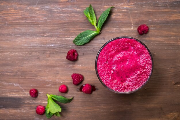 Blueberry in raspberry fresh in a glass on a wooden board.