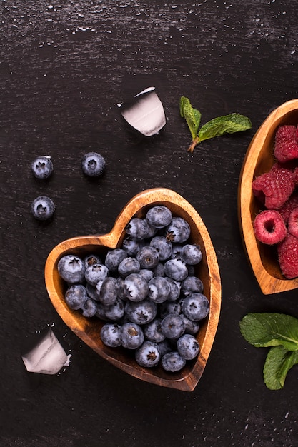 Blueberry and raspberry in heart shaped wooden bowls