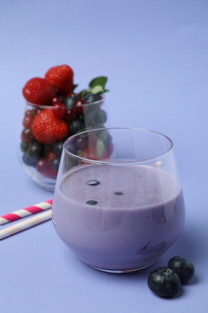 Blueberry smoothie, ingredients and straws on violet background