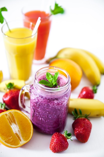 Blueberry smoothies on a white surface with berries