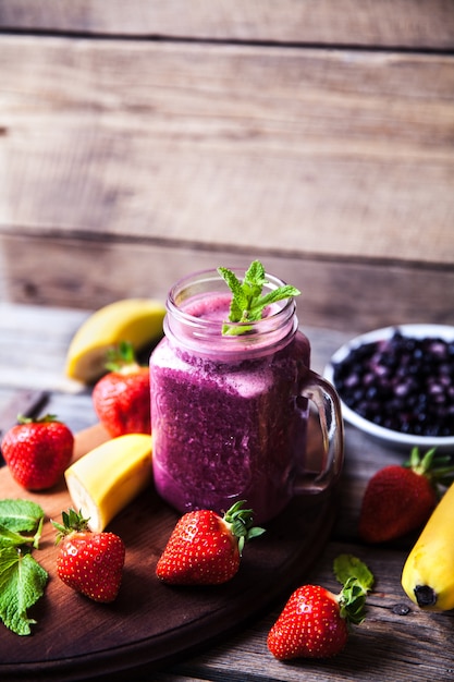 Blueberry smoothies on a wooden table with fruits. Vitamins