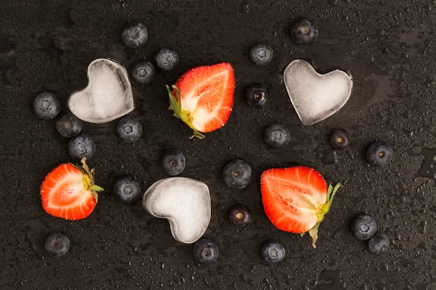 Photo blueberry, strawberry over wet black stone