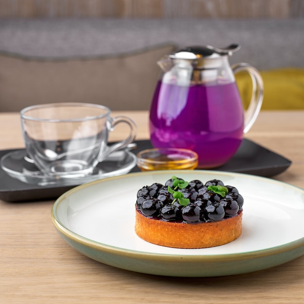 Черничный пирог и голубой чай гороховый цветок травяной чай. тайский голубой чай подается с медом и черничным пирогом на деревянном столе