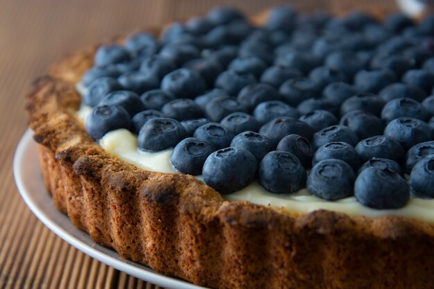 Blueberry tart or cake with cream and berries. Homemade dessert, wooden board.