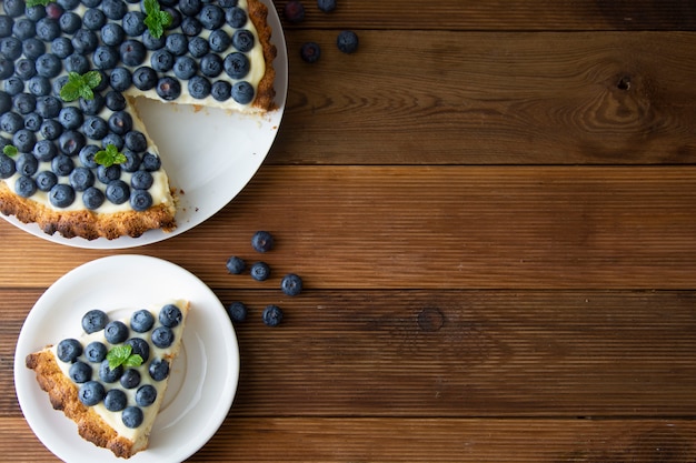 Blueberry tart or cake with cream and berries. Homemade food, wooden, rustic background.