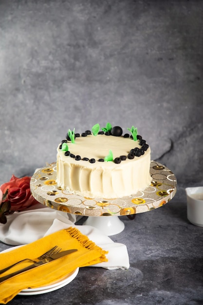 ブルーベリー ホワイト ケーキの生クリームとバラの花のナイフとフォークは、カフェで焼いた食べ物のナプキン側面図に分離されたボード上で提供されます