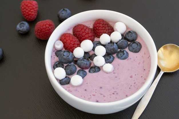 Blueberry yogurt with fresh berries on a wooden table.