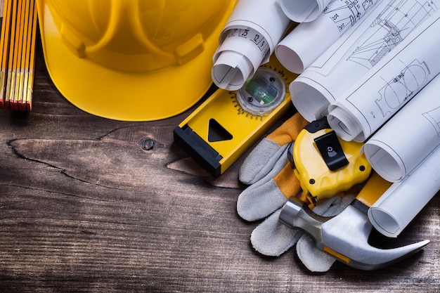 Blueprint rolls and set of construction tools on vintage pine wooden board maintenance concept