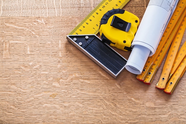 Blueprints square ruler tape measure and wooden meter on oak board construction concept