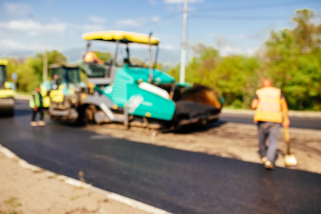 建設現場の背景がぼやけているため、新しいアスファルト道路舗装道路建設作業員が敷設されています