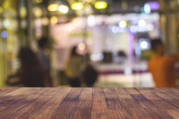 Foto offuschi il ristorante o la caffetteria del caffè vuoto della tavola di legno scura con il fondo leggero vago dell'estratto del bokeh dell'oro.