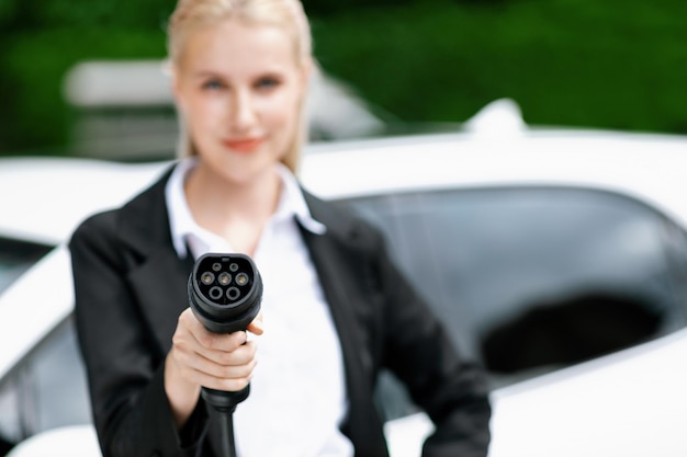 Blur closeup progressive woman holding and point EV plug for electric vehicle