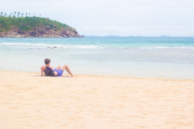 blur image of man sitting on the beach.