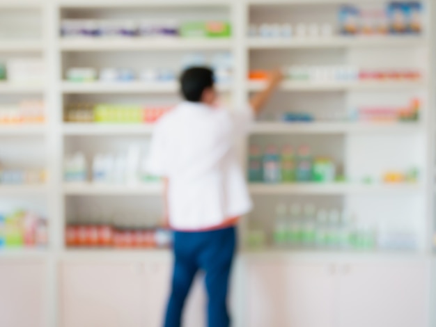 Blur image of pharmacist taking medicine from shelf in the pharmacy