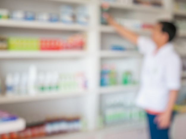 Blur image of pharmacist taking medicine from shelf in the pharmacy