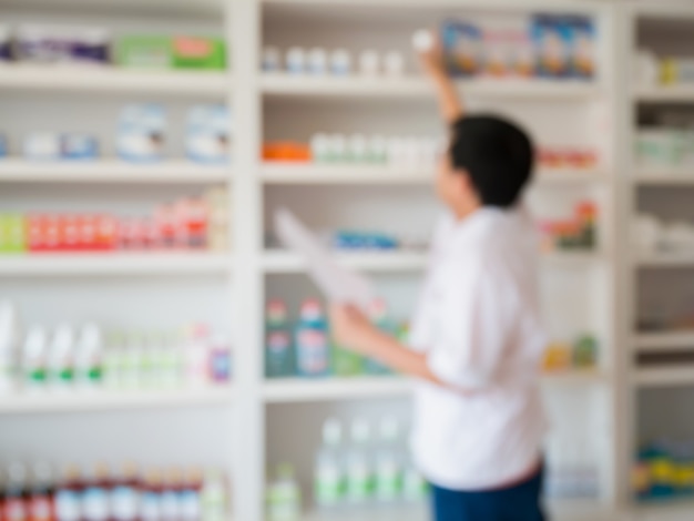 Blur image of pharmacist taking medicine from shelf in the pharmacy