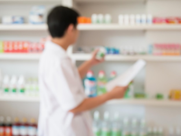 Blur image of pharmacist taking medicine from shelf in the pharmacy