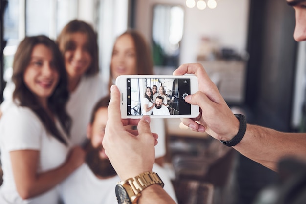 Blur portrait of blissful young best friends with hands holding phone on foreground