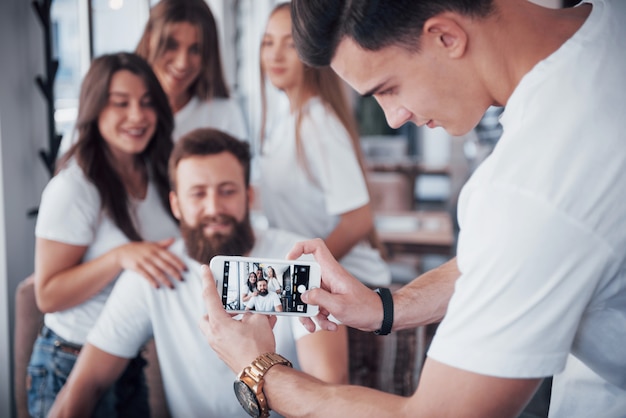 Blur portrait of blissful young best friends with hands holding phone on foreground