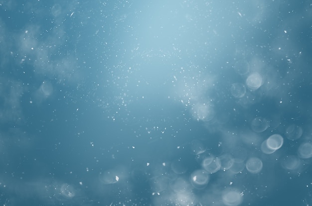 Blurred abstract background with bokeh and snowflakes in the air on a blue background