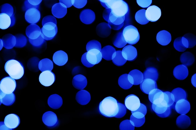 Luci di natale sfocate con texture glitter blu astratte sfocate su sfondo nero