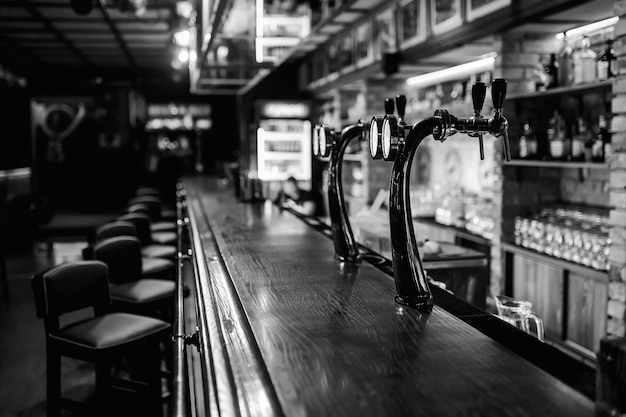 Blurred background of classic wooden bar counter with empty chairs and alcohol in the background