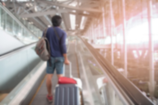 Размытый фон человека, тащащего чемодан багажа в аэропорту, фон путешествия