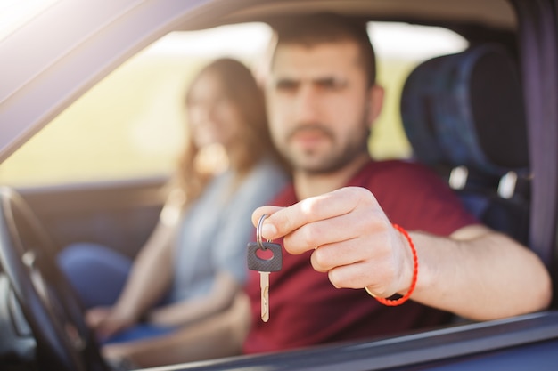 Blurred background. Man holds keys from vehicle, sells his automobile