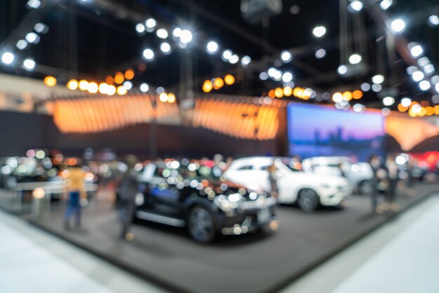 Blurred background of new cars displayed in luxury showroom with light bokeh, motor show event.