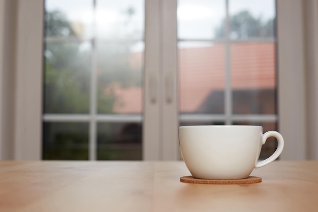 写真 キッチンのぼかした背景とお茶の白いカップ